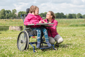 Working with disability / A disabled child in a wheelchair relaxing outside with a special needs carer.