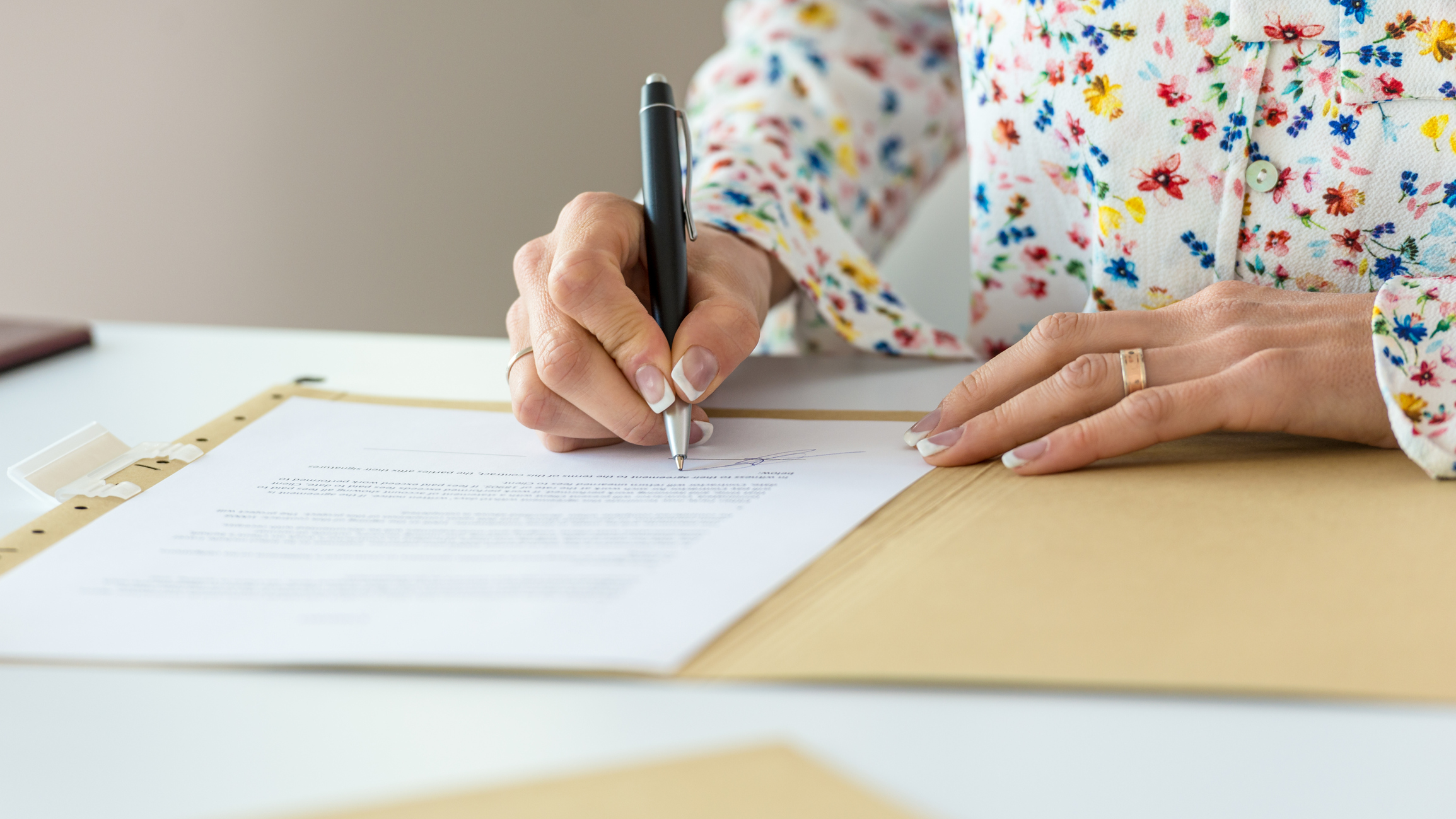 Avoid Common Estate Planning Mistakes - A woman wearing flowered shirt, signing documents